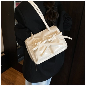 Creamy white bow shoulder bag with pleated pockets shown on a person in a black blazer