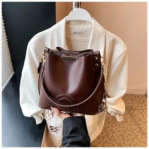 Detail view of coffee brown bucket bag showing textured wide strap and metal buckle