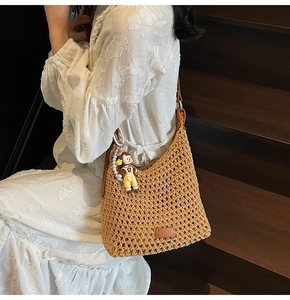 Detailed close-up of brown crochet straw bucket bag with cute pearl doll charm accessory