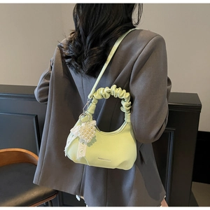 Detail of light green hobo bag with pleated handle and pearl heart charm on model