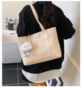 Chic beige tote bag detail featuring a plush cloud charm and minimalist branded label