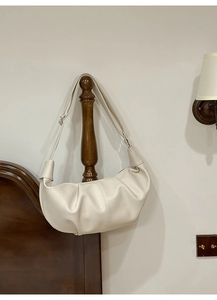 Detail view of the cream pleated dumpling bag showing pebbled leather texture and strap