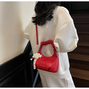Close-up of red pleated handle mini bag with pearl heart charm on white hoodie