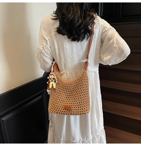 Detail of hand-woven cotton shoulder bag with leather patch and cute cartoon doll charm