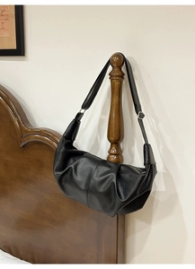 Close-up of black pleated faux leather hobo bag with adjustable strap and textured finish