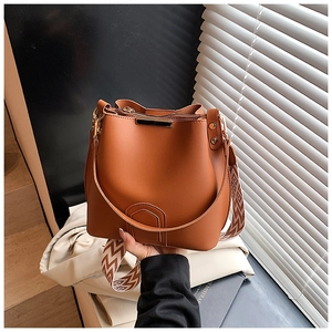 Detail of caramel bucket bag with geometric patterned wide strap and metallic accents