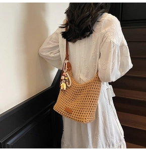 Detail of hand-woven bucket bag with doll charm and pearl chain on a white lace dress