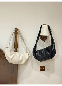 Detail view of white and black wrinkled crescent bags with lychee grain leather texture