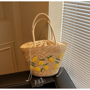 Detail of handwoven straw tote featuring lemon embroidery and drawstring closure