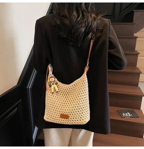 Detail of hand-woven beige cotton bucket bag with brown leather strap and doll charm