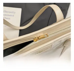 Detailed close-up of golden zipper hardware and leather texture on a beige underarm bag