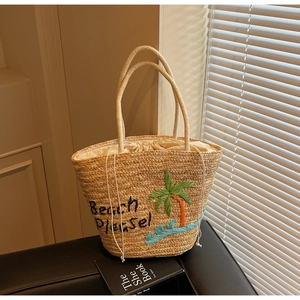 Detailed shot of straw beach tote featuring Beach Please embroidery and palm tree design