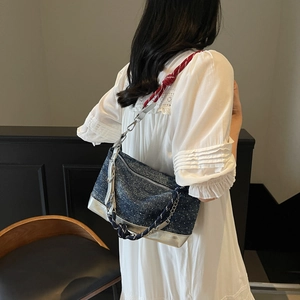 Detail of denim shoulder bag featuring a tri-color woven rope strap and silver hardware