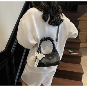 Detail of black ruched handle handbag with pearl heart charm and lace ribbon decoration