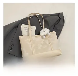 Macro detail of cream tote bag featuring marble texture and a white cloud plush charm