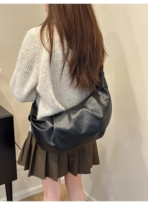 Detail of black leather croissant bag showing lychee texture and slouchy pleated design