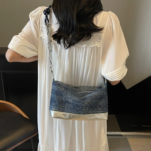 Detailed back view of a blue denim shoulder bag with white polka dots and silver chain