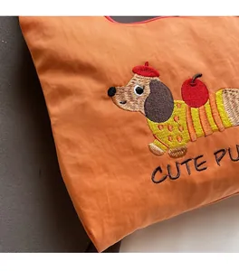 Detail of cute dachshund embroidery on an orange canvas bucket bag with soft texture