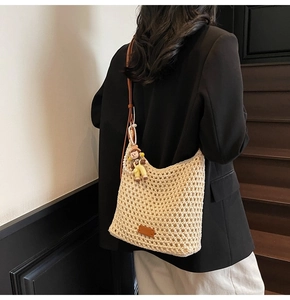 Detail of hand-woven crochet hobo bag with adjustable leather strap and cute doll charm