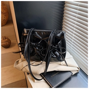 Detailed close-up of a black glossy bow handbag on an elegant white background