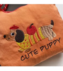 Detailed macro view of cute dachshund embroidery and Cute Puppy text on orange nylon bag
