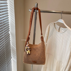 Detailed view of brown woven cotton tote bag featuring a leather strap and cute doll pendant