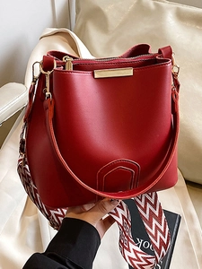 Red leather bucket bag with gold metal trim and decorative patterned wide strap