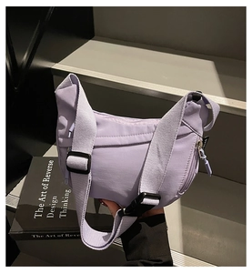 Close-up of lavender crescent crossbody bag with adjustable strap on stone background