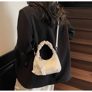 Mini beige pleated handbag with pearl heart charm and lace bow detail on stairs
