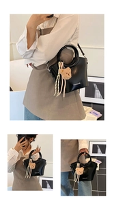Dettaglio di borsa nera lucida con ciondolo a forma di orsetto e lunghe frange chic