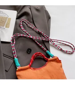 Detail of bright orange bucket bag with colorful woven straps and Matisse art book