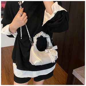 Détail du sac plissé argenté avec nœud en dentelle perlée et bandoulière en chaîne