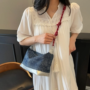 Detail of denim shoulder bag with bold red white braided strap and white fringe accent