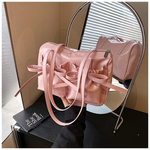 Detail view of pink glossy PU leather underarm bag with decorative bows and pockets