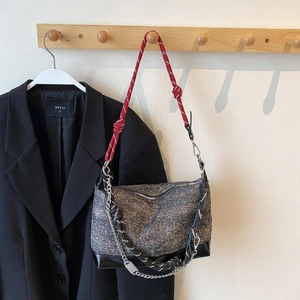 Detail of grey tweed shoulder bag with red climbing rope strap and metallic chain accents
