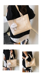 Detail of beige textured leather tote bag with soft cloud-shaped plush keychain charm