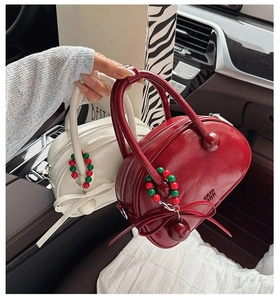Detail view of retro mini bowling bags in glossy wine red and cream with beaded charms