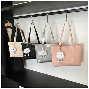 Detail of four colorful tote bags in PU leather featuring cloud charms on a clothing rack