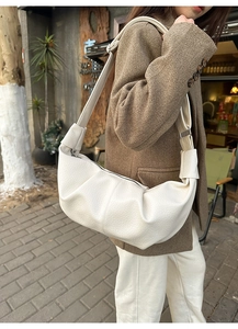 Detailed view of the white crocodile-textured faux leather crossbody crescent bag on model
