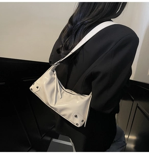 Detail der cremefarbenen Schultertasche mit silbernen Nieten zum schwarzen Blazer