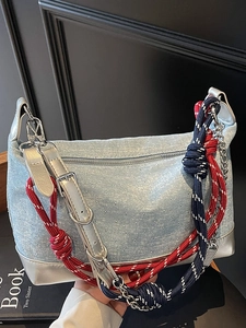 Blue denim shoulder bag with silver studs and braided strap in a modern street style
