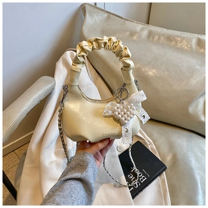 Détail du sac coquille blanc crème avec poignée froncée et breloque perle en cœur