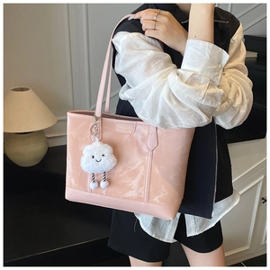 Pink glossy tote bag detail with white cloud plush charm and metallic brand logo