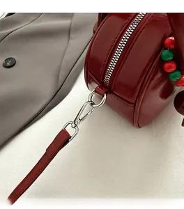 Close-up of wine red patent leather bag showing silver hardware and beaded decoration