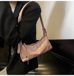 Nahaufnahme der rosa glänzenden Halbmondtasche mit silbernen Nieten und Metallschnalle