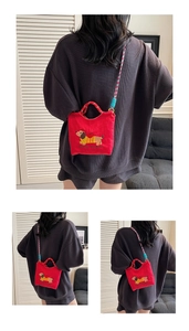 Detail of red canvas bucket bag featuring cute dachshund embroidery and striped strap