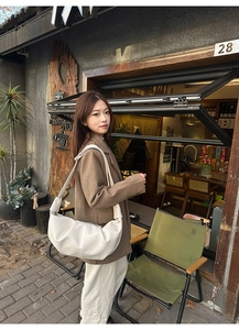 Detail view of large white pleated dumpling bag with soft texture in outdoor street style