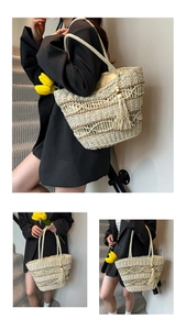 Detail view of woven straw tote bag with brown wave pattern and fringe tassel decoration