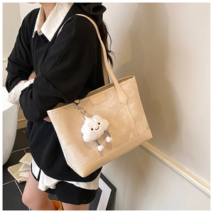 Detail of a beige marble-textured tote bag with a white cloud charm and square metal plate