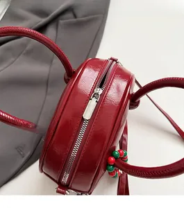 Detail view of red patent leather bowling bag with smooth silver zipper and bead charm